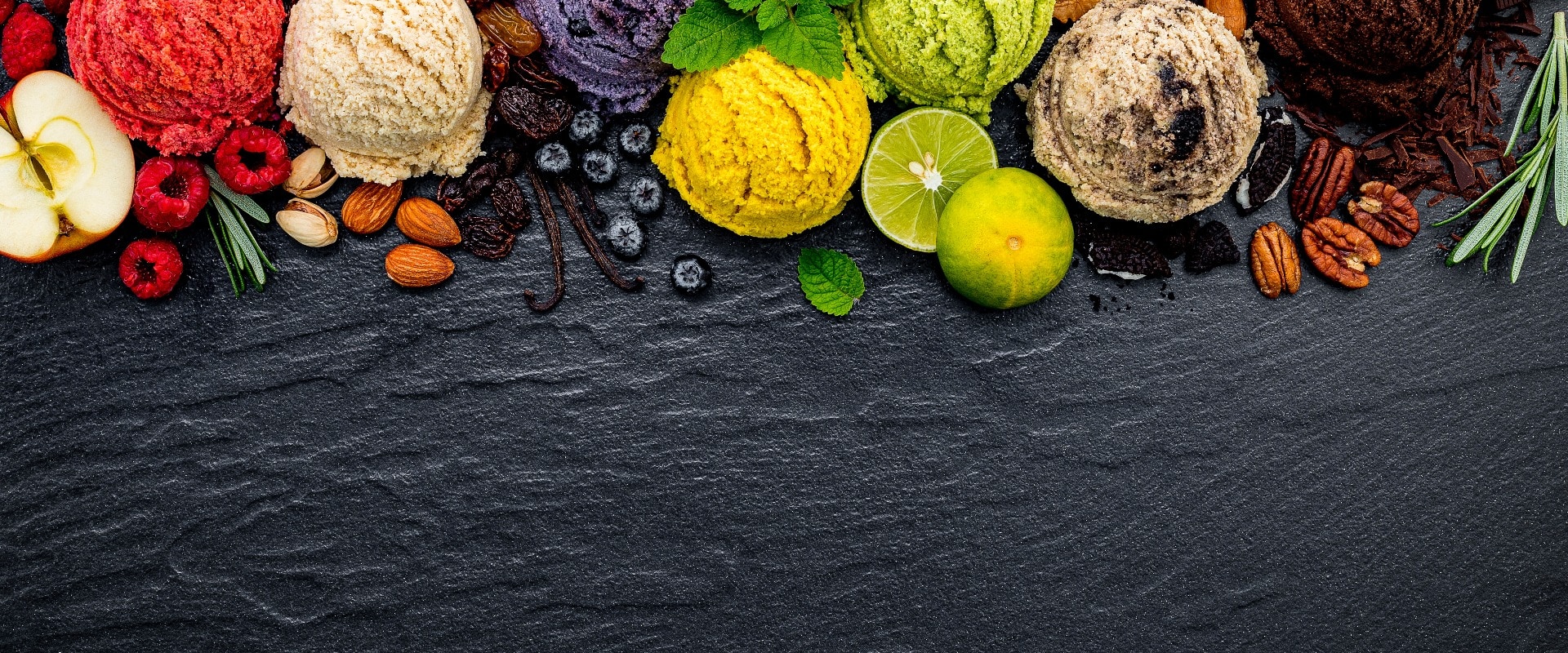 Various of ice cream flavor ball blueberry ,lime ,pistachio ,almond ,orange ,chocolate and vanilla set up on dark stone background . Summer and Sweet menu concept.